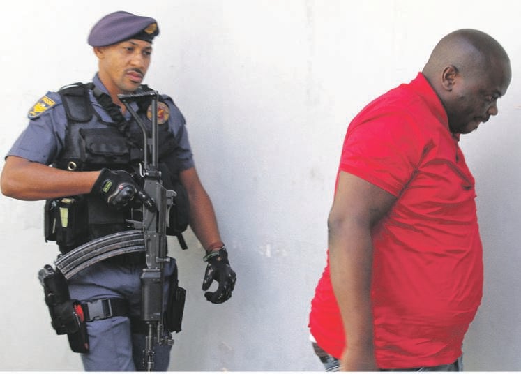 An armed cop escorts murder accused Vusi Sihlabela after his case was postponed to next year. 