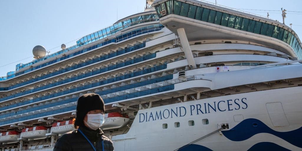 A member of the media wearing a face mask walks past the Diamond Princess cruise ship at Daikoku Pier.