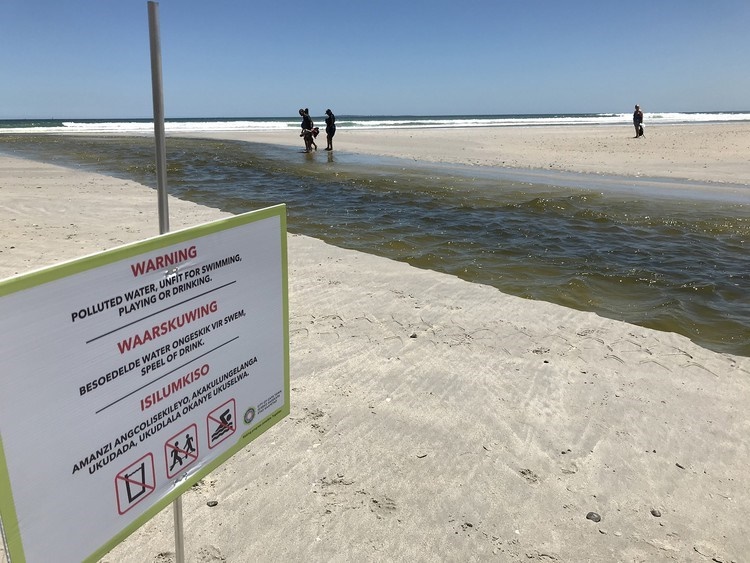 When GroundUp visited the mouth of the Milnerton Lagoon on 16 December, the water was clearly heavily polluted and the City had erected a number of warning signs. (Photo: Steve Kretzmann/WCN)