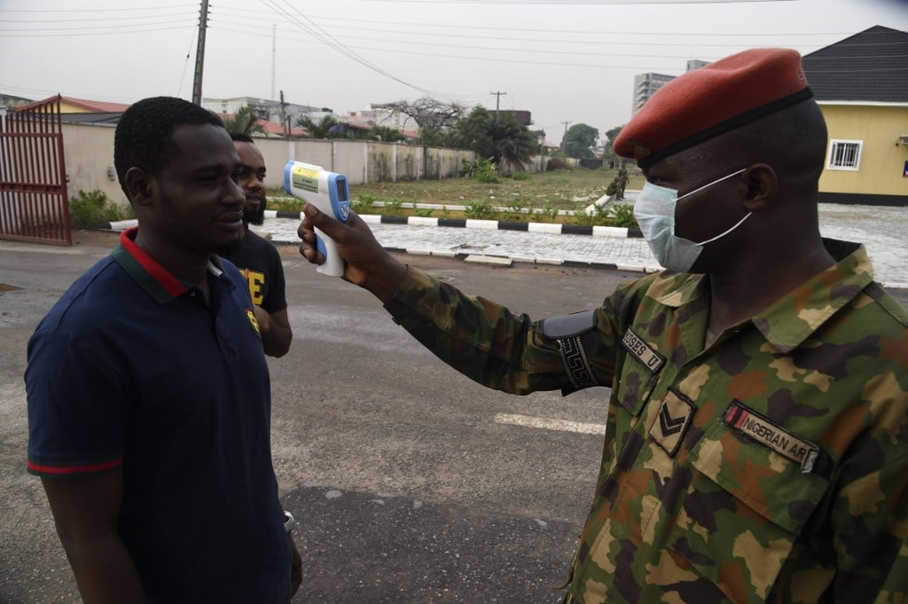 A soldier checks the body temperature of a visitor