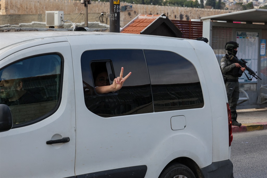 An Israeli settler flashes the V for victory sign as they drive past Palestinian Muslims gathering for Friday prayers in east Jerusalem on December 29, 2023, amid ongoing battles between Israel and the militant Hamas group in Gaza.