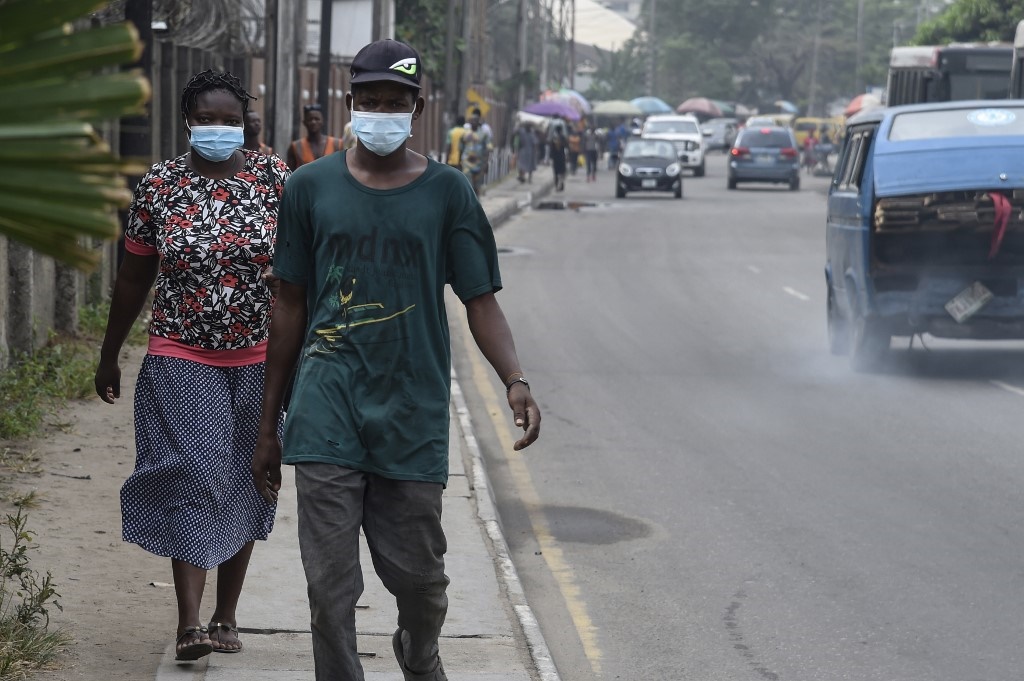 People walk along a main road wearing face masks at Yaba in Lagos. (Pius Utomi Ekpei / AFP)