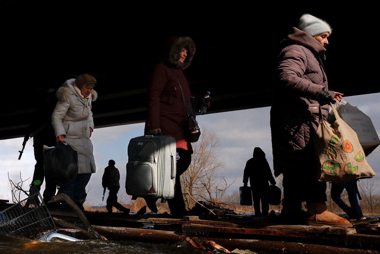 People fleeing advancing Russian forces file across wooden planks crossing Irpin River below a destroyed bridge in Ukraine, March 9, 2022. Thomas Peter/Reuters