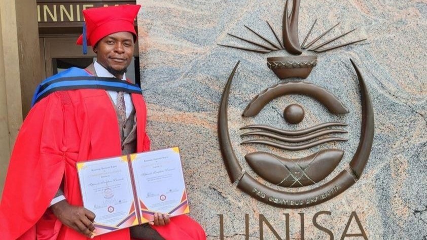 Pemphero Mphande posing in a red gown, while holding what he claimed was his honorary certificate from Unisa. 