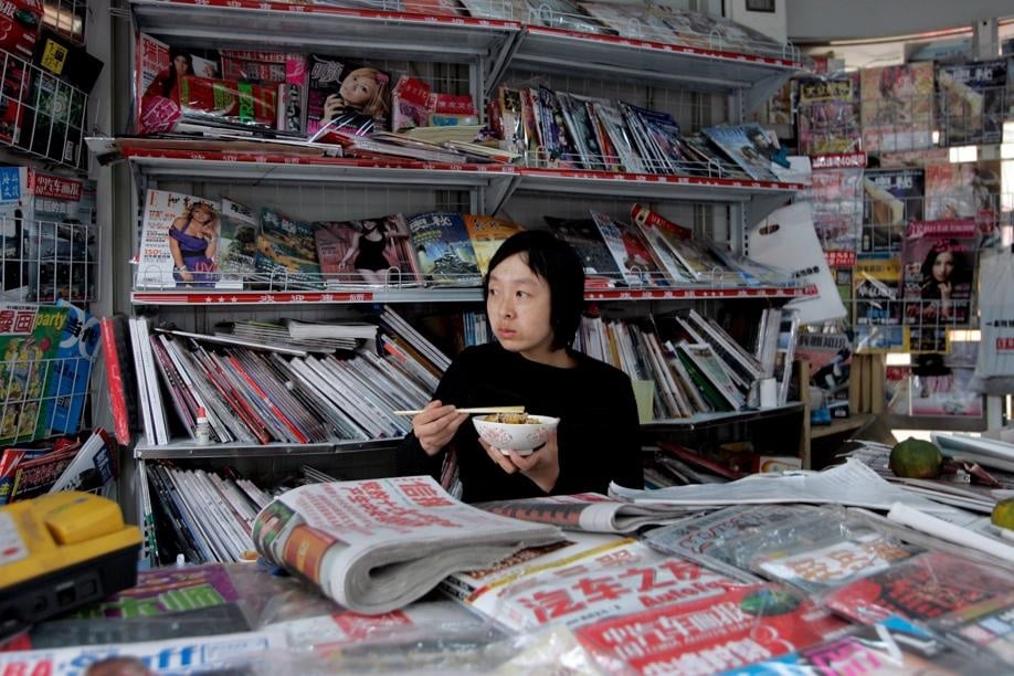 A Chinese woman eats at a newspaper and magazine kiosk in Beijing, China. Picture: EPA/Michael Reynolds 