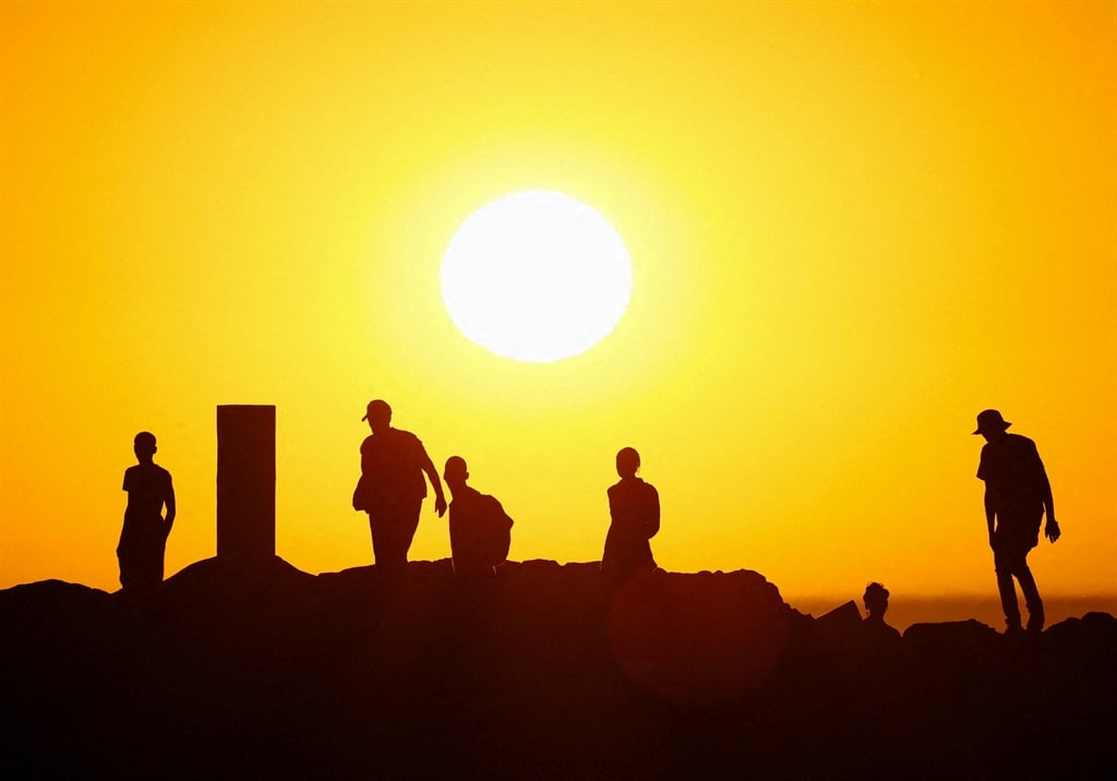 People walk on the rocks during sunset at Sea Point promenade in Cape Town on Wednesday. 