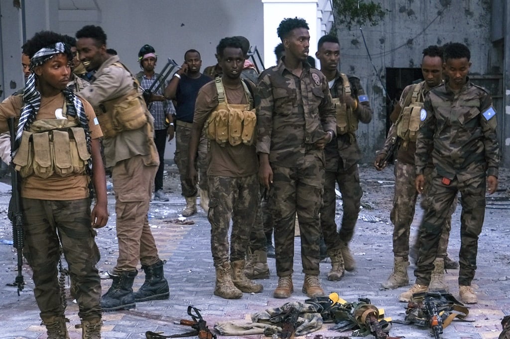 Police officers stand near the bodies of alleged Al-Shabaab militants who had been killed after the siege at the Mogadishu Municipality Headquaters in Mogadishu in January 2023. (Photo by Hassan Ali ELMI / AFP)