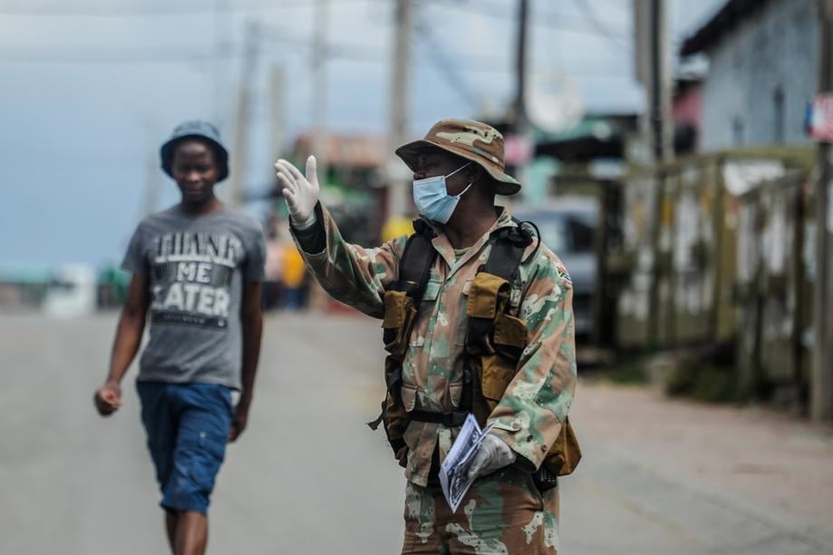 A member of the SANDF is seen giving residents of 