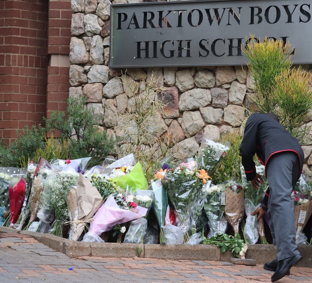 A learner places flowers outside Parktown Boys' High after the death of a pupil. (Palesa Dlamini)