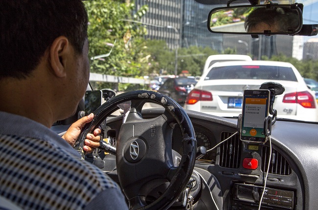 A taxi driver is using Didi Dacha App while driving on the way