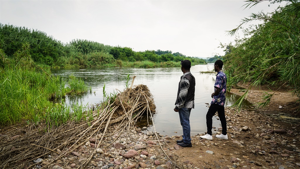 Enoch Mpianzi’s brother Yves Kadilo (right) stands near a river bank where a water activity took place that claimed the life of his brother. (Chanté Schatz, News24)