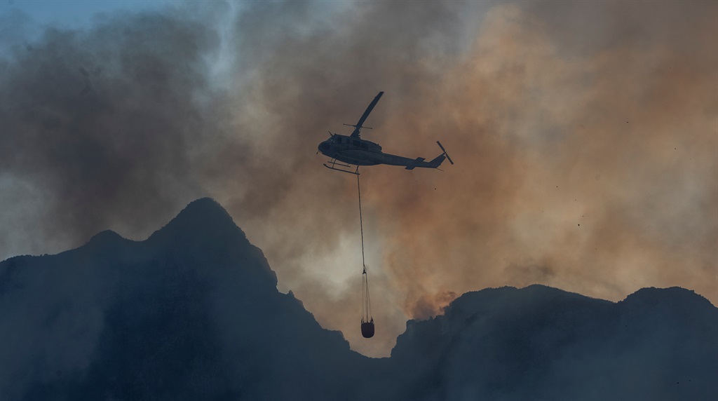 A water chopper hovers over University of Cape Town. It is reported that a wildfire spread from the slopes of Table Mountain to University of Cape Town and burned the historic campus library. (Photo by Brenton Geach/Gallo Images via Getty Images)