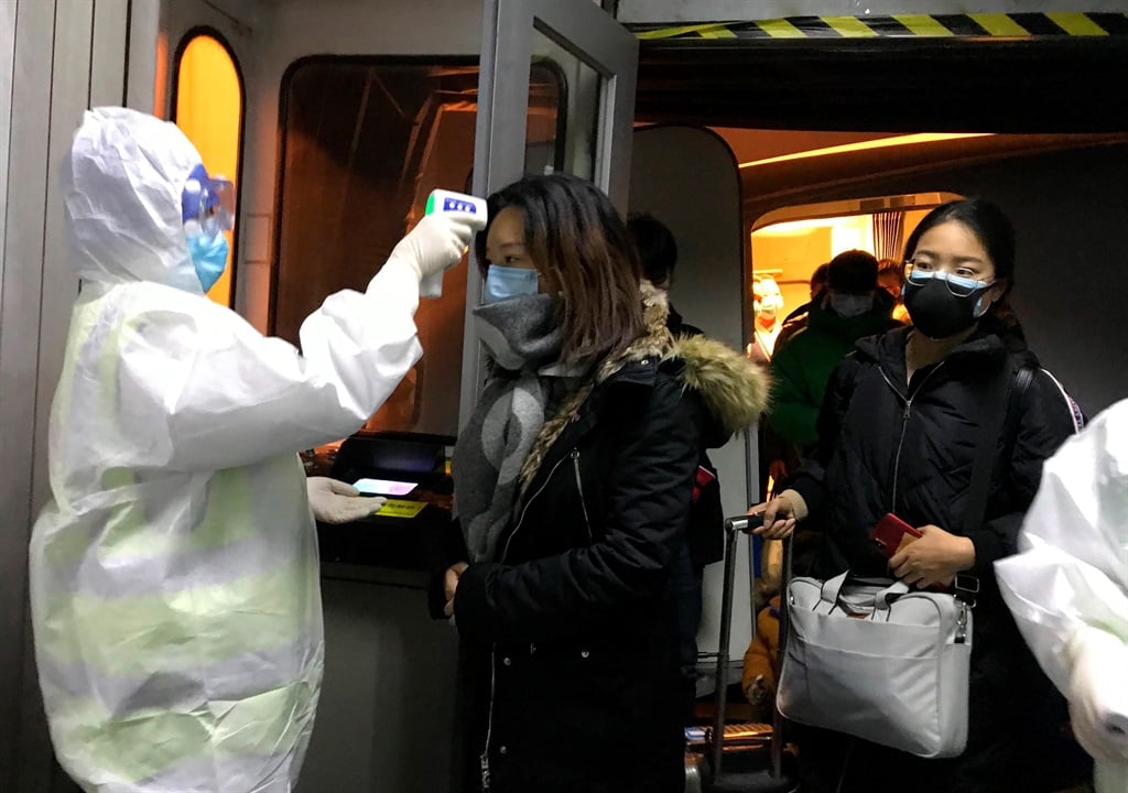 Health officials in hazmat suits check body temperatures of passengers arriving from Wuhan, China, on January 22, 2020, at the airport in Beijing.