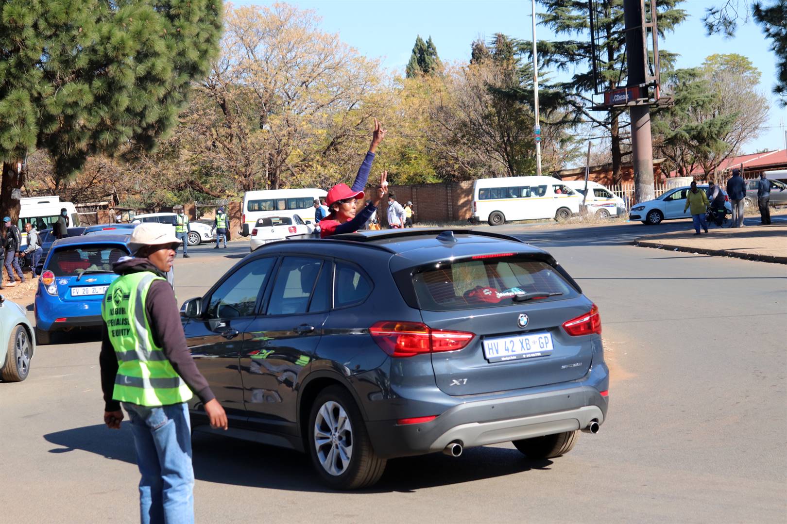 A member of Zondo’s church appears on the sunroof of a moving vehicle with hooting sprung as they celebrate the move of his case to Pretoria High Court. Photo by Sifiso Jimta