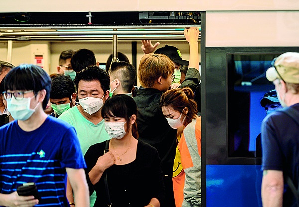 Thaise pendelaars dra mediese ­maskers op ’n trein in Bangkok. Foto: Gallo Images/Getty Images