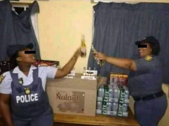 COPS are investigating two cops  in uniform, holding what appears to be bottles of beer and posing next to packs of liquor.