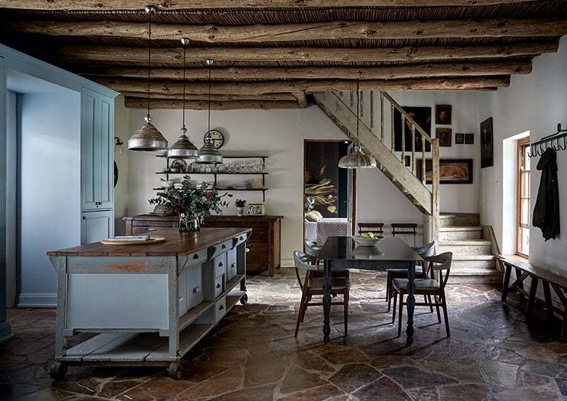 An elegant dining table made by contemporary South African designer Gregor Jenkin contrasts beautifully with the historical details that surround it – from the exposed wooden beams and reed ceiling to the restored wooden sash window and handcrafted staircase built from salvaged scaffolding planks. Mismatched slasto completes the eclectic look.