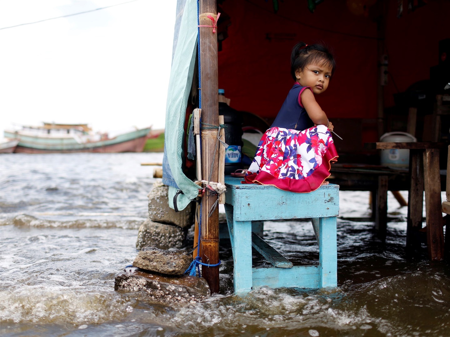 A 2-year-old sits on a bench at Kali Adem port, amid high tides due to rising seas and sinking land, north of Jakarta, Indonesia, on November 20, 2020. Willy Kurniawan/Reuters