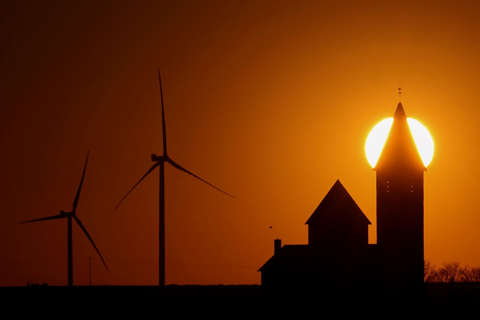 Power-generating windmill turbines beside a church in Noreuil village, during sunset at a wind park near Cambrai, France, on March 18, 2022.Pascal Rossignol/Reuters