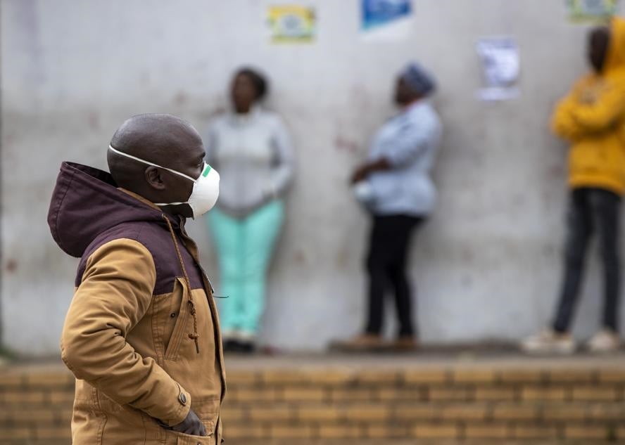 A man wearing a face mask to protect himself against the Covid-19 coronavirus, walks past people queuing for shopping in Duduza, east of Johannesburg on Thursday (April 2 2020). Picture: Themba Hadebe/AP  Photo