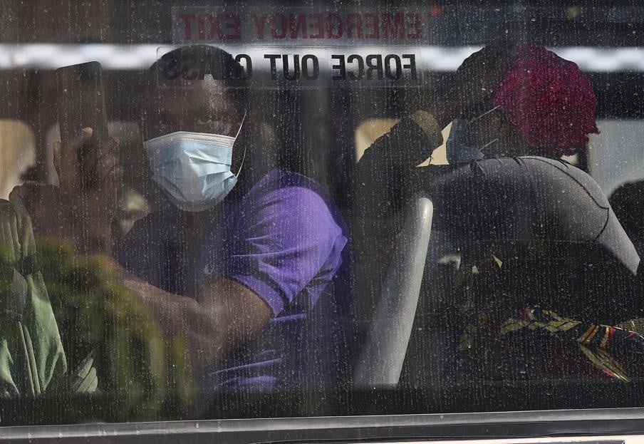 Foreign migrants wait on a bus after police remove