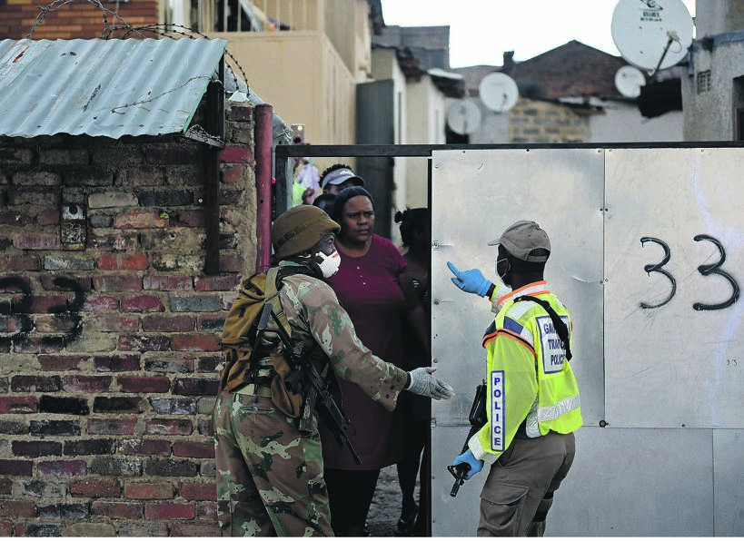 A metro police officer and an SA National Defence Force member order people to stay in their houses and keep away from the streets in Alexandra township, Johannesburg. Picture: Teogo Letsie